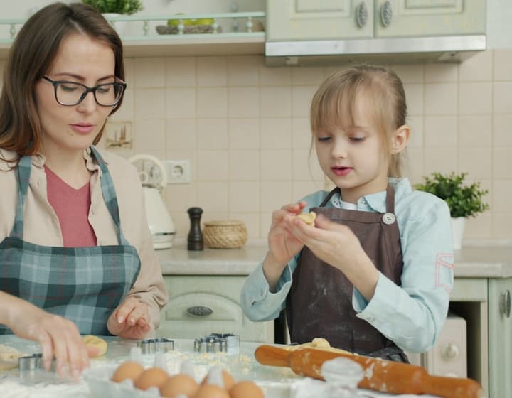 A caregiver and child baking together in a bright kitchen